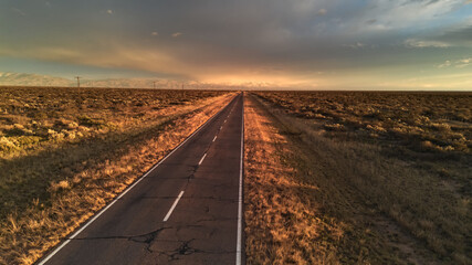 Asphalt road across the desert at sunrise. Aerial view.