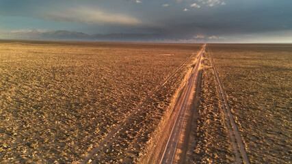 Asphalt road across the desert at sunrise. Aerial view.