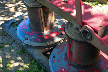 Details of agricultural machinery with faded red paint and metallic parts, indicating active use....