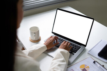 Woman using laptop with white screen mockup on desk