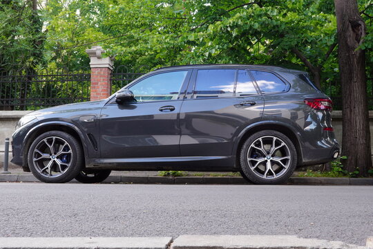 Bucharest, Romania &ndash; May 11, 2025: Closeup side view of BMW X5 xDrive 45e parked on street along fence of garden