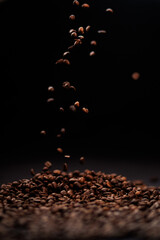 Falling roasted coffee beans on a dark background