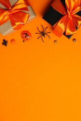 Vertical Halloween flat lay composition with gifts, pumpkin, bat, spiders and comfetti. Happy Halloween holiday concept