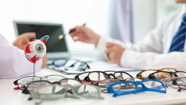 An ophthalmologist recommends eyeglass frames fit patient face after measuring eyeglasses prescription cut lenses fit eyeglasses prescription. Eye measurement and eyeglass cutting with ophthalmologist