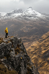 Adventurous hiker in a vibrant yellow jacket captures breathtaking mountain vista background