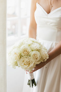 bride holding bouquet with white roses