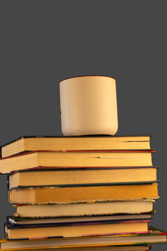 stack of books with cup of coffee on top, isolated on dark grey background