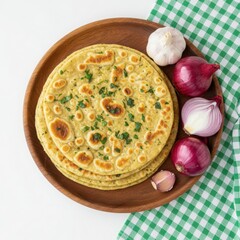 Freshly baked garlic naan bread with red onions and garlic cloves on a wooden plate with green checkered cloth