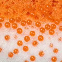 Macro close up of bright orange bubbles and foam on a textured surface creating a vibrant abstract pattern