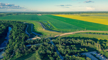 Obraz premium Aerial photo of a rural park and river next to contrasting green and yellow farm fields. Summer landscape.