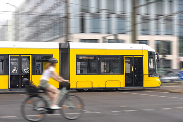 Yellow tram and cyclist. Urban transport in motion. Dynamic intersection