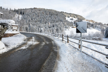 A snowy road with a sign on the side