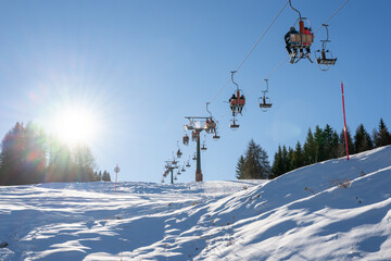 A ski slope with a line of ski lifts and a sunny day