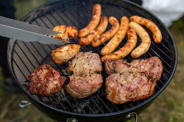 Grilled sausages and meat on charcoal barbecue. Close-up of assorted sausages, pork, and chicken...