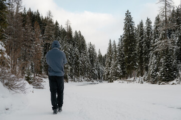 A man is walking in the snow with a hood on his head