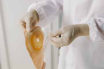 A nurse prepares a colostomy bag to replace for a patient.