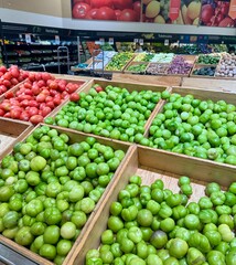 wood crates of green tomatillos and red tomatoes at a well-stocked grocery store produce section