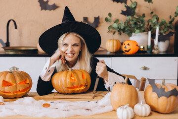 Smiling witch carving pumpkins for Halloween party