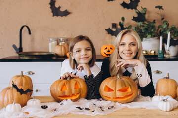 Mother and daughter carving pumpkins for Halloween party