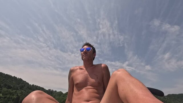 Time lapse tourist on a stand up paddle board in the lake of Levico in Trentino, Northern Italy. Man is forty years old and of Caucasian origin