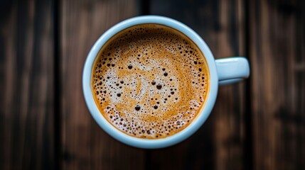 Top view of hot coffee in blue mug on wooden background for cozy morning breakfast concept