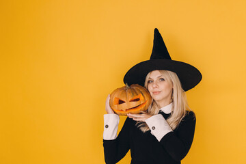 Halloween witch holding jack o' lantern with yellow background