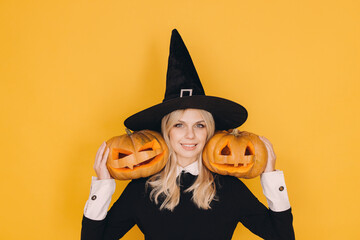 Smiling witch holding two jack o' lanterns celebrating Halloween