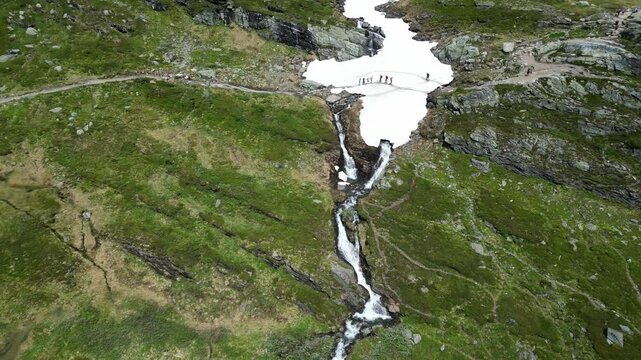 Hikers Walking on Snow Trail to Trolltunga Norway, aerial view from a drone