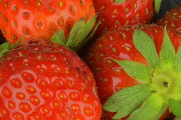 Macro shot of ripe red strawberries on a black backdrop. Ripe strawberries on a black stone backdrop. Close-up and view from above