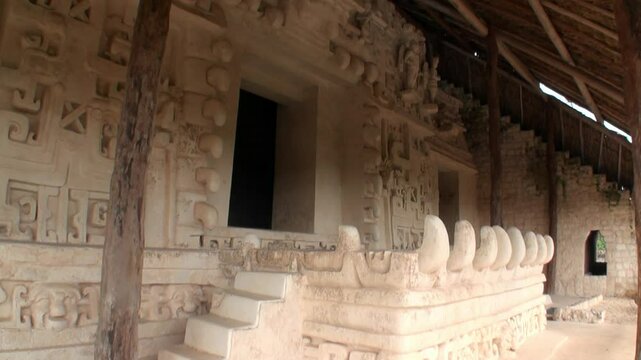 Sunlight illuminates the intricately carved facade of Acropolis at Ek Balam in Mexico. Detailed glyphs and stone sculptures reveal the artistry of the Maya civilization and architectural ingenuity.