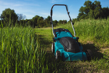 Electric Lawn Mower Creating Path Through Tall Green Grass Field