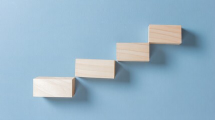 Wooden blocks in staircase formation on blue, minimalist composition symbolizing growth and progress
