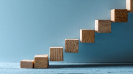 Wooden blocks in staircase formation on blue, minimalist composition symbolizing growth and progress
