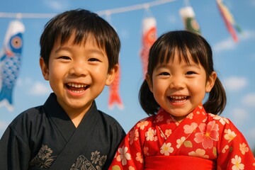 Two smiling Japanese children in kimonos celebrate Children's Day with Koinobori in the background. Concept of: Celebrating Japanese kids together.
