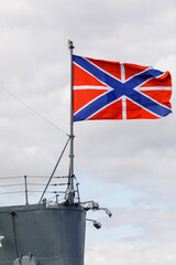 The Russian naval flag flies above the Cruiser Aurora, with the ship's deck and equipment visible...