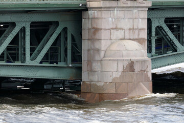 A close-up of a support pillar of the Palace Bridge, partially submerged in the Neva River with...