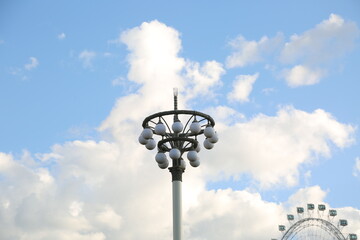 Beautiful summer blue sky with street metal design lamps and ferris wheel on blue clouds background...