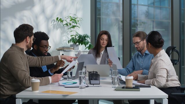 Diverse business team discussion together businesswomen businessmen women men talking showing papers documents coworkers planning analyzing in office briefing meeting conference multiethnic colleagues
