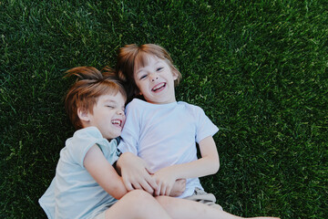 Happy children enjoying a sunny day, smiling while lying on the green grass, creating joyful...