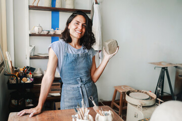 Latin ceramic artist shaping clay in pottery studio with apron, creative process and cultural identity