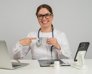A female doctor sits at a table and recommends pills. 