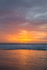 Ocean sunset with orange sky and waves reflecting the light.