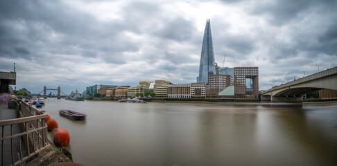 London cityscape featuring the Shard, Tower Bridge, and London Bridge under a cloudy sky.