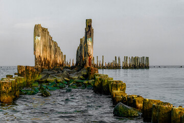Old ruined wooden pier and a sandy beach on the Baltic Sea