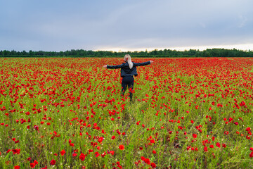 Woman, view from the back, stands with arms outstretched to the sides in the middle of a vast...