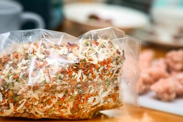 Mix of dried fruits for soups in a plastic bag on a table, containing pieces of dried onion,...