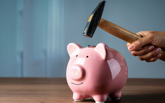 Primer plano de una mano con un martillo en una alcanc&iacute;a rosa, expectativas de ahorro de dinero, espacio de copia