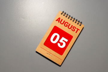 Wooden block calendar with the date August 05 and spikelets of wheat.