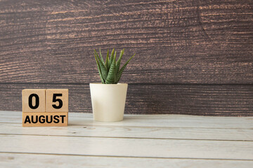 Wooden block calendar with the date August 05 and spikelets of wheat.