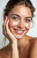 Obraz premium Smiling young woman touches her healthy facial skin. Natural makeup, glowing hydrated skin on white background. Portrait of beautiful girl model, skincare, cosmetology, cosmetics, spa.